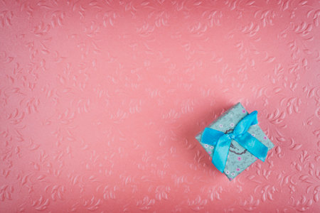 Small blue gift box. Minimal composition on pastel pink background.の写真素材