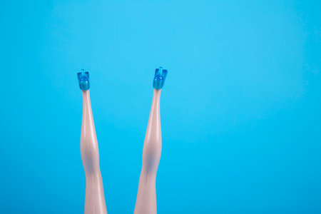 Female doll legs upside down on light blue backgroundの写真素材