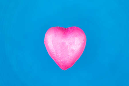 Heart dipped in pink paint on blue textured background. Minimal Valentines day concept.の写真素材