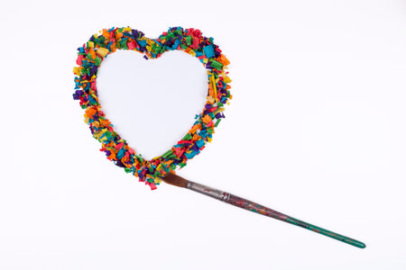 Heart shape made of colorful sawdust with art paint brushの写真素材
