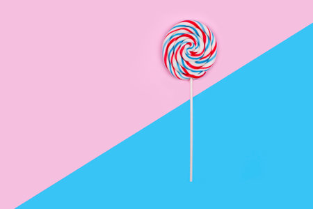 Colorful lollipop on pink and blue pastel backgroundの写真素材