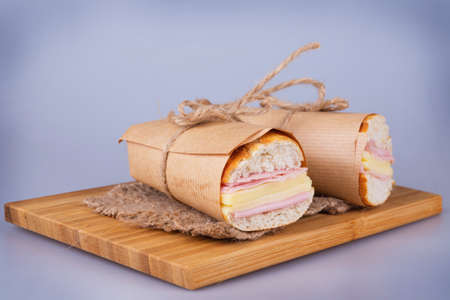 Tasty ham and cheese sandwich on wooden chopping boardの写真素材