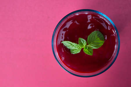 Tasty cheesecake in a glass cup on pink background