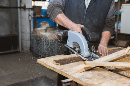 Close-up of a carpenter working circular saw. The carpenter saws wooden blocks and wood slates.の写真素材