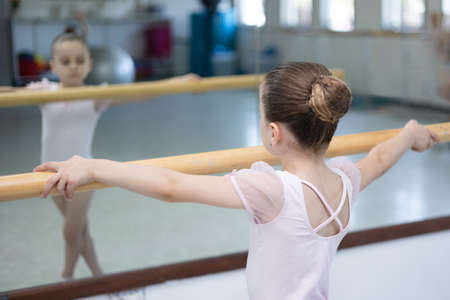 Cute little girl toddler ballerina in pale pink tutu and ballet shoes practicing dance moves.の写真素材