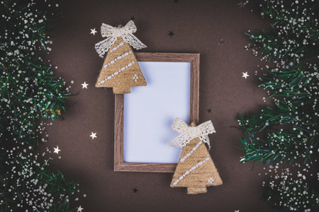 Christmas holidays card composition on brown background with snow covered fir branches and mock up.の写真素材