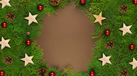 Christmas card on brown background with Thuja branches, red balls, wooden stars and place for text.