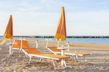 Sun loungers and closed umbrellas on the sea beach. Beach without people. Vacation conceptの写真素材