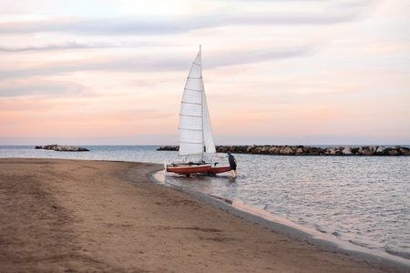 Viserbella,Italy-September 05,2022:Empty sea beach on sunset background with sailing catamaran.のeditorial素材