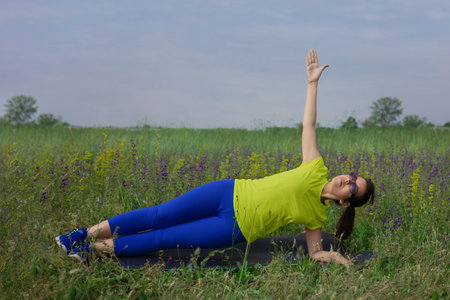 Young hispanic woman doing exercising on mat in the city park. Breathing practices and mental healthの写真素材