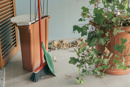 Closeup broom and leaves of ivy Cleaning and preparing the balcony garden for summerの写真素材