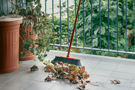 Closeup broom and leaves of ivy. Cleaning and preparing the balcony garden for summer.の写真素材