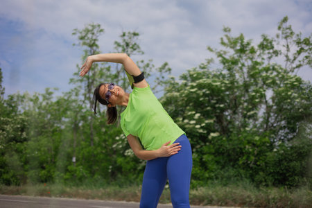 Young hispanic woman in colored sportswear doing exercise in the city park.Healthy lifestyle conceptの写真素材