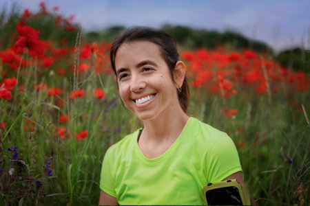 Portrait young hispanic woman in colored sportswear on background of poppy field with space for textの写真素材