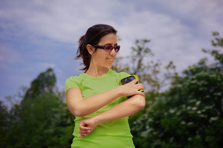 Young hispanic woman in colored sportswear stopped to rest after a run. Sports gadgets.の写真素材