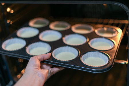 Closeup female hand holding iron mold with group homemade dough for pumpkin muffins.の写真素材
