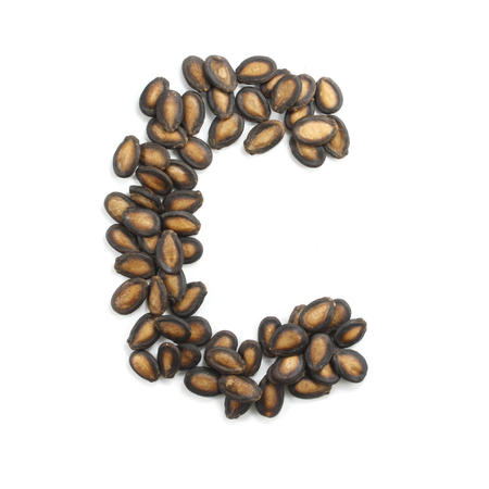 letter C made of watermelon seeds isolated on white backgroundの写真素材