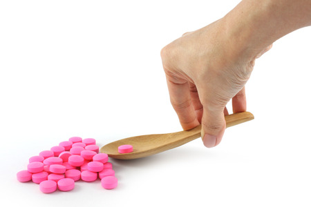 Pink Medicine on wood spoon  on white backgroundの写真素材