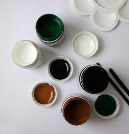 Open bottles with colored acrylic paints on white background