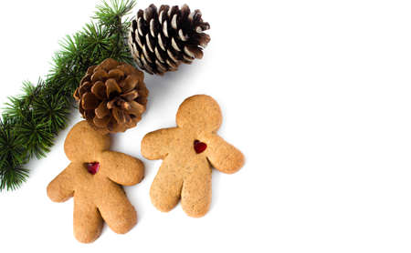 A pair of gingerbread lovers with hearts with a branch of a christmas tree and a pine coneの写真素材