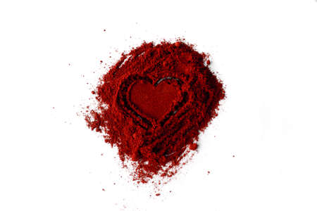 Close-Up Of Ground Red Chili Pepper Over White Background. Pile of ground Paprika isolated in heartの写真素材