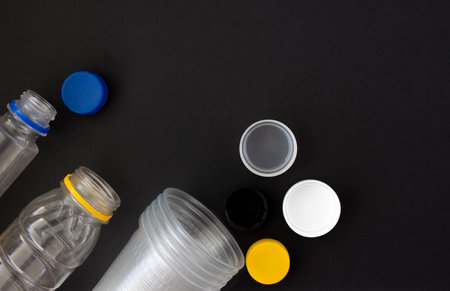 disposable plastic tableware on a black background. Environmental pollution. Space for text