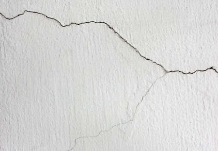 A crack in the white wall. Crack concrete wall texture background.