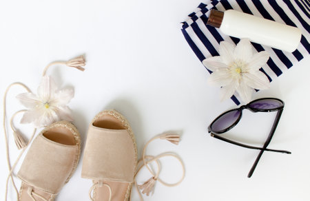 Summer Flat lay. Summer sandals, white flowers, sunglasses and a white bottle.Top view. Creative background.の写真素材