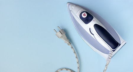 Iron for ironing things on a blue background. Top view, copy spaceの写真素材