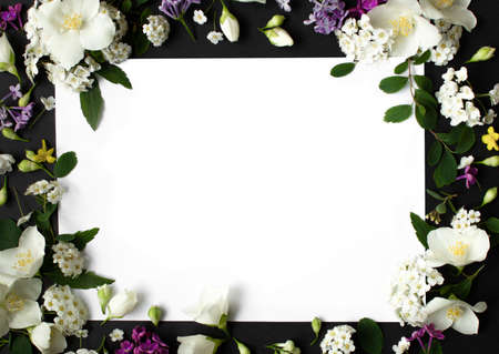 Floral frame made of different spring flowers on black background. Flowers flat lay. Space for textの写真素材