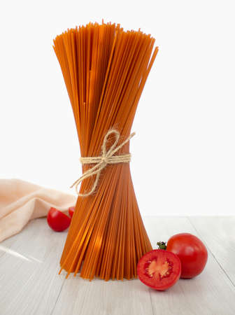 Bunch of raw italian red pasta with tomatoes on light backgroundの写真素材