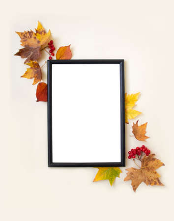 Blank mock up photo frame, autumn leaves and berries on beige background. Flat lay, top view, copy...