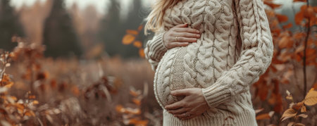 Pregnant woman in knitted sweater against autumn landscape. Banner, copyspace. High quality photoの素材