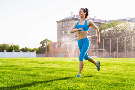 Incredibly beautiful, athletic girl does exercises at the sports city stadium on a warm summer evening. Making a stand upside down on hands.の写真素材