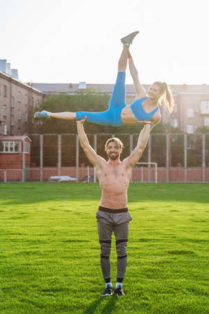 Incredibly beautiful, athletic girl does exercises at the sports city stadium on a warm summer evening. Making a stand upside down on hands.の写真素材