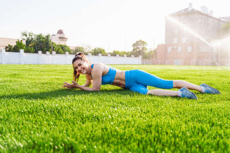 Beautiful, attractive, charming brunette having fun at the football stadium on a warm summer evening. Wrinkles from water from the field irrigation system, cooling under drops of water.の写真素材