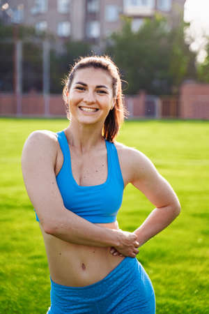 Athletic muscled young woman in a sports wearing doing fitness exercises. Fitness woman posing at the stadium. Healthy athletic lifestyle.の写真素材