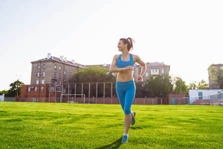 Athletic muscled young woman in a sports wearing doing fitness exercises. Fitness woman posing at the stadium. Healthy athletic lifestyle.の写真素材