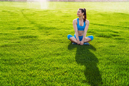 Athletic muscled young woman in a sports wearing doing fitness exercises. Fitness woman posing at the stadium. Healthy athletic lifestyle.の写真素材