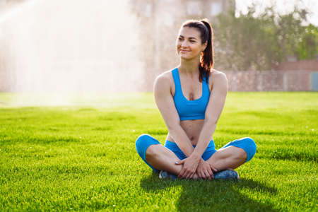 Athletic muscled young woman in a sports wearing doing fitness exercises. Fitness woman posing at the stadium. Healthy athletic lifestyle.の写真素材