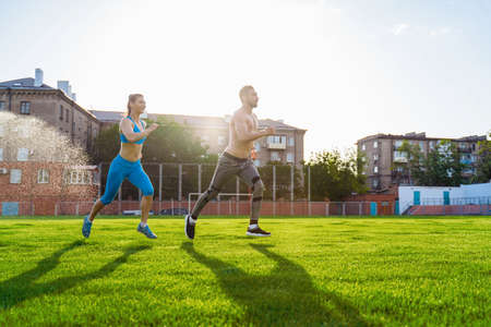 Athletic muscled young woman in a sports wearing doing fitness exercises. Fitness woman posing at the stadium. Healthy athletic lifestyle.の写真素材