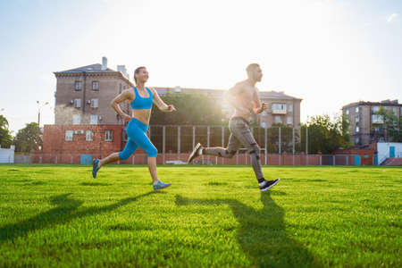 Athletic muscled young woman in a sports wearing doing fitness exercises. Fitness woman posing at the stadium. Healthy athletic lifestyle.の写真素材