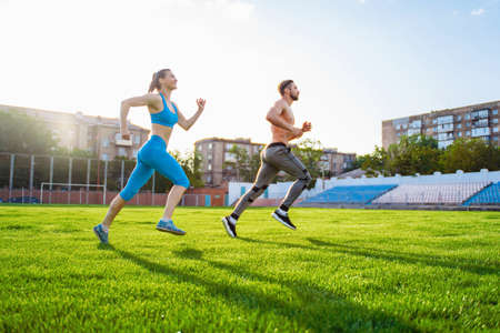 Athletic muscled young woman in a sports wearing doing fitness exercises. Fitness woman posing at the stadium. Healthy athletic lifestyle.の写真素材