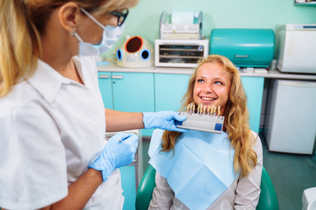 Experienced, professional woman dentist trying on a palette with a set of colors for dental crowns. The whitening procedure requires careful preparation. Healthy teeth smile.の写真素材