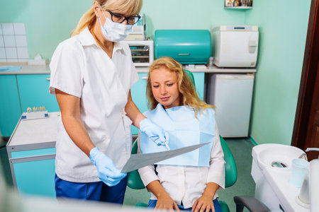 Dentist and the patient examine image of the dental cavity, teeth, in order to choose a treatment in consultation with medical equipment. Correction of bite deficiencies. Deep tooth canal treatment.の写真素材