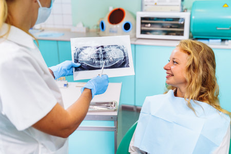 Dentist and the patient examine image of the dental cavity, teeth, in order to choose a treatment in consultation with medical equipment. Correction of bite deficiencies. Deep tooth canal treatment.の写真素材