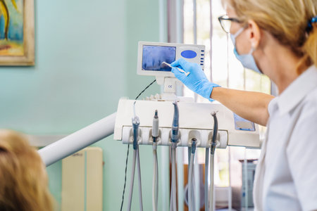 Highly qualified dentist offers the patient effective solutions to dental problems. Examination of the oral cavity according to the jaw image. The doctor shows the patient an x-ray.の写真素材