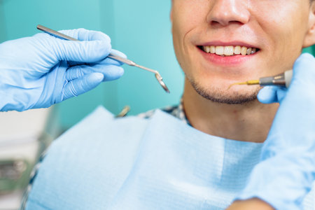 Close-up of the dentist's hands with medical devices. Large detail - dentist's mirror, curling and probe. Resolving dental problems effectively with confident, professional gestures.の写真素材