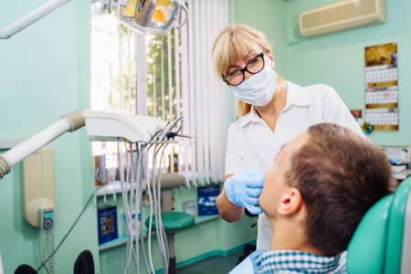 Highly qualified dentist offers the patient effective solutions to dental problems. Examination of the oral cavity according to the jaw image. The doctor shows the patient an x-ray.の写真素材