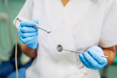 Close-up of the dentist's hands with medical devices. Large detail - dentist's mirror, curling and probe. Resolving dental problems effectively with confident, professional gestures.の写真素材